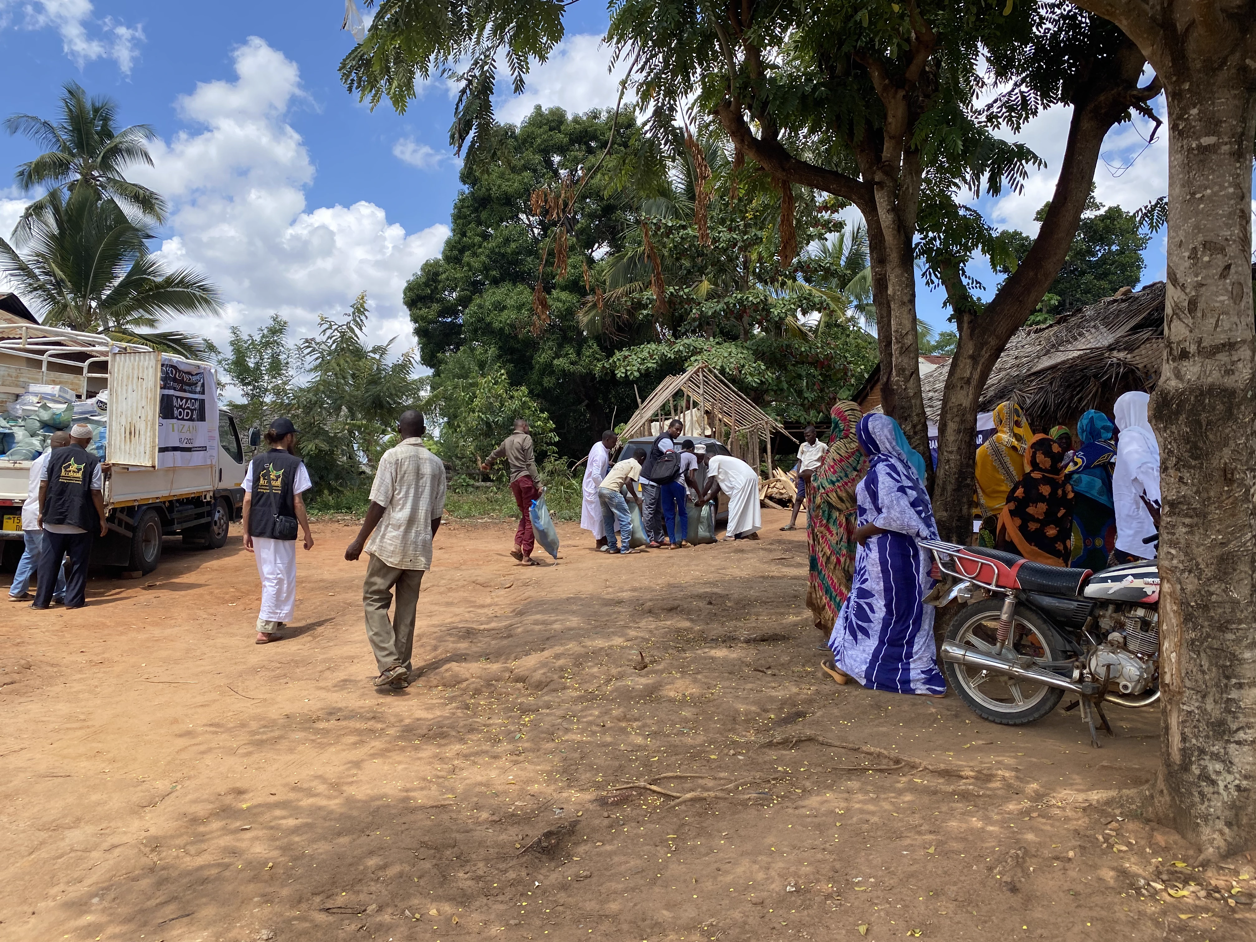 Crowd of villagers and volunteers unloading and distributing Ramadan food parcels
